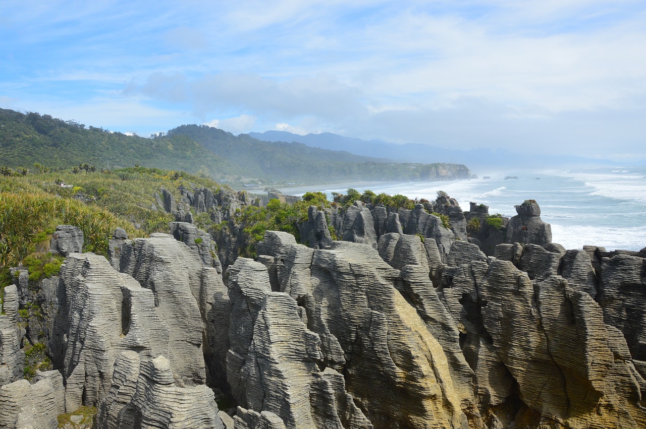 Blick auf eine Küstenregion, wo im Vordergrund die besonderen Felsformationen der Pancake rocks zu sehen sind